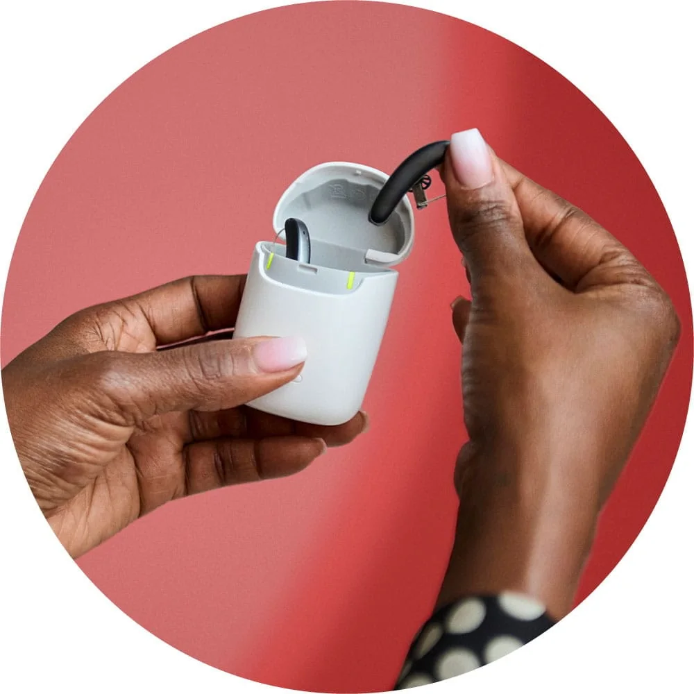 Rechargeable hearing aid being placed into its charging case